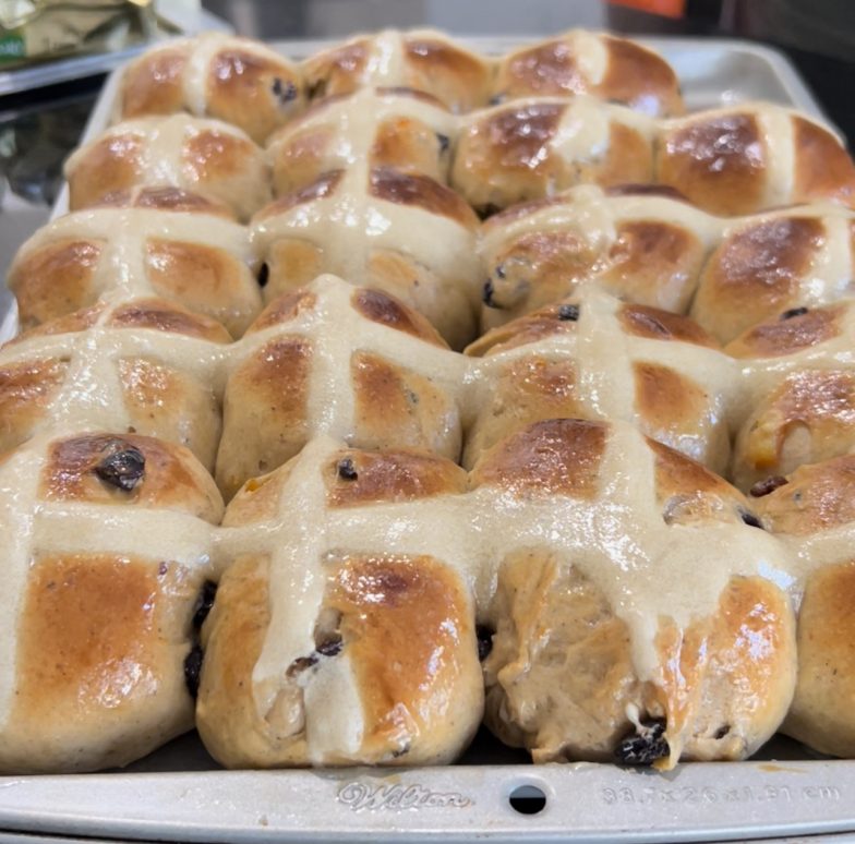 a bunch of hot cross buns on a baking tray