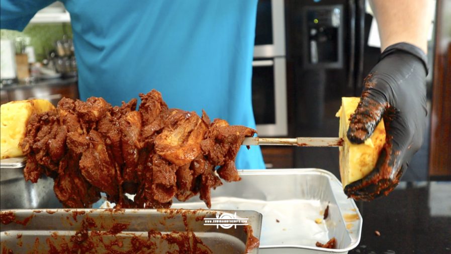 2 slices of pineapple and a bunch of marinated pork meat in a spit rod
