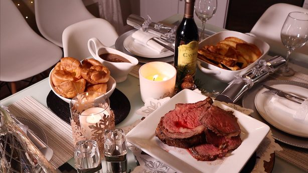 Roast beef, yorkshire pudding, gravy, caymus wine on the table ready for roast dinner