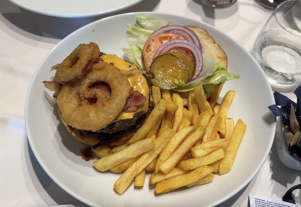 Cheeseburger topped with an onion ring, with a side of fries
