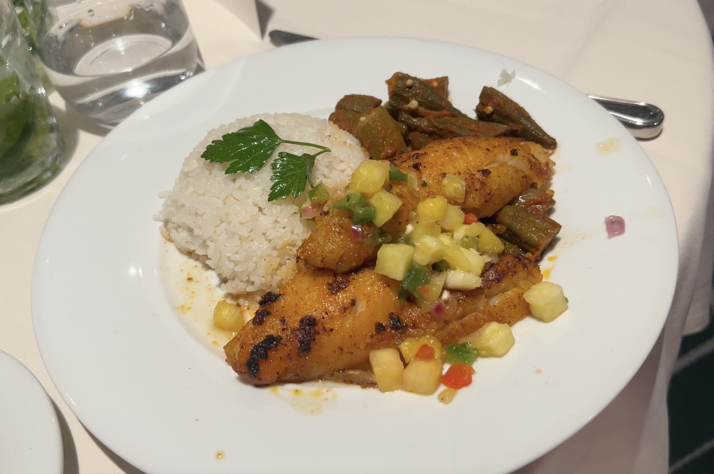 Grilled fish with rice and mango salsa on a white plate