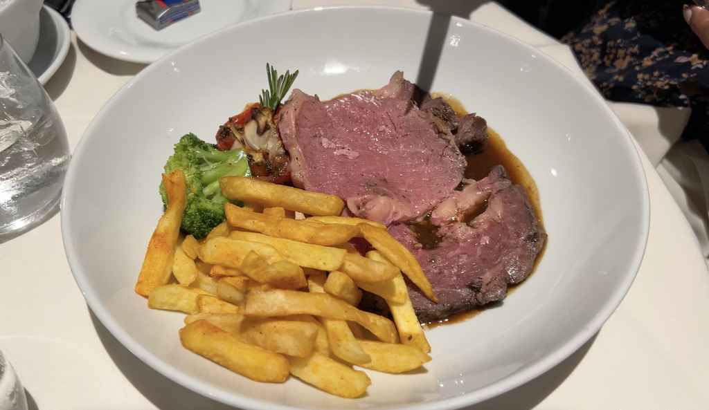 Sliced prime rib with French fries and vegetables in a bowl