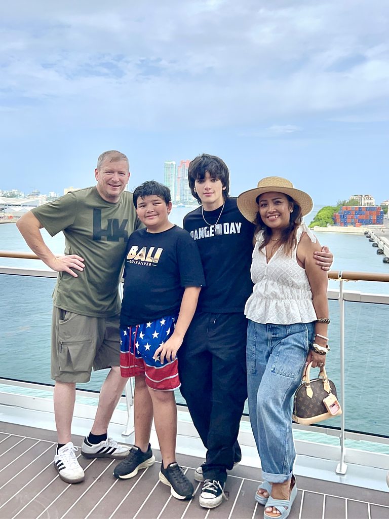Family of four posing at the ship rail on embarkation day