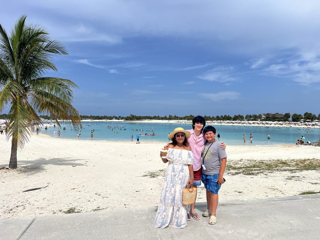 Family on a white sand beach at Ocean Cay with turquoise water behind