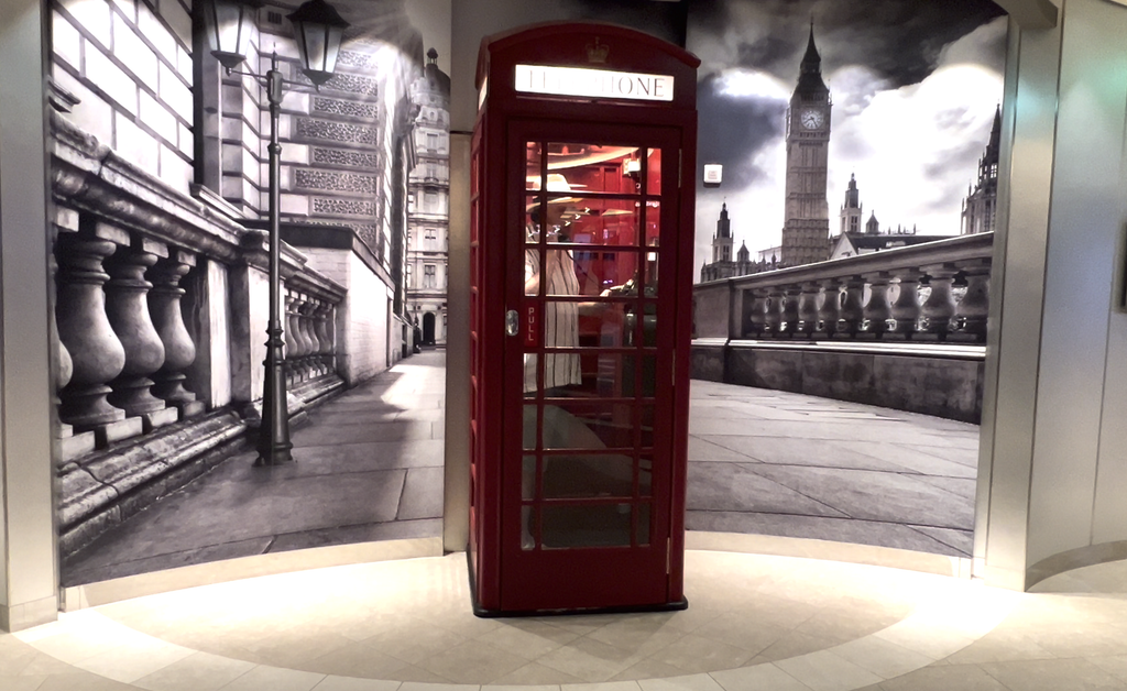 Red British-style telephone booth in front of a London mural