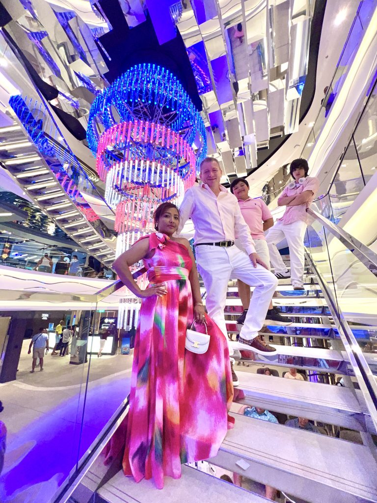 Woman in a bright pink dress on the staircase of the ship atrium
