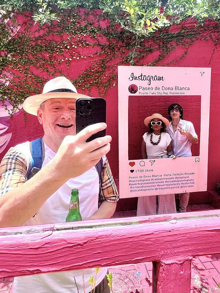 Man taking a photo at a pink wall with an Instagram-style frame
