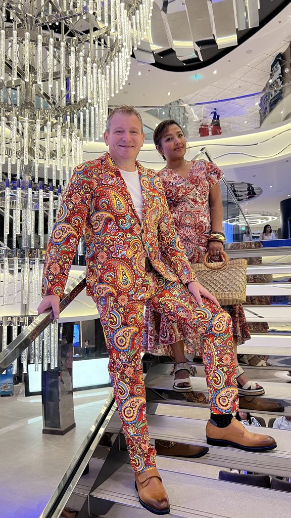 Two people in matching colorful patterned outfits on a ship staircase