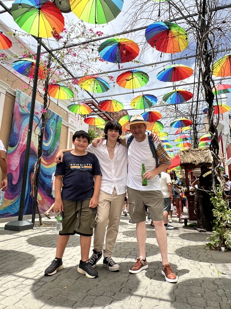 Family walking under colorful umbrellas in a Puerto Plata street