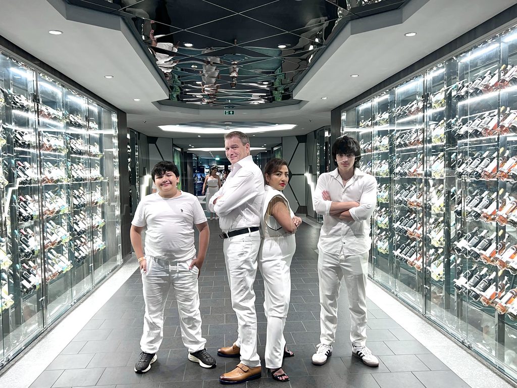Four people in white outfits standing in a mirrored ship corridor