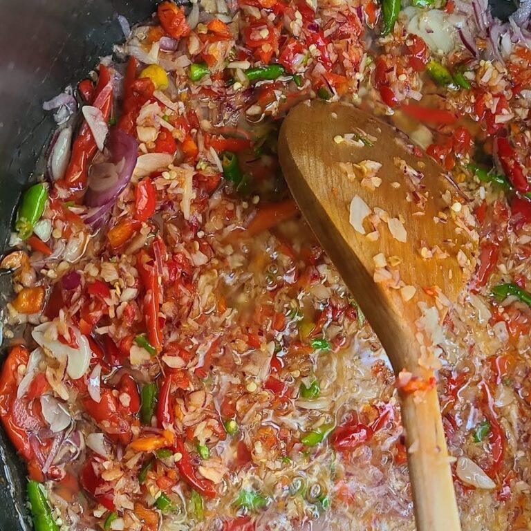 Garlic chili oil with fried shrimp paste (sambal terasi goreng) sizzling in a wok with a wooden spoon